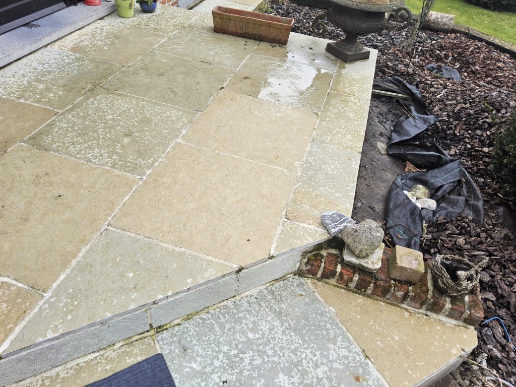 Terras met natuurstenen tegels; vochtige vloer door recente regen zichtbaar op de stenen