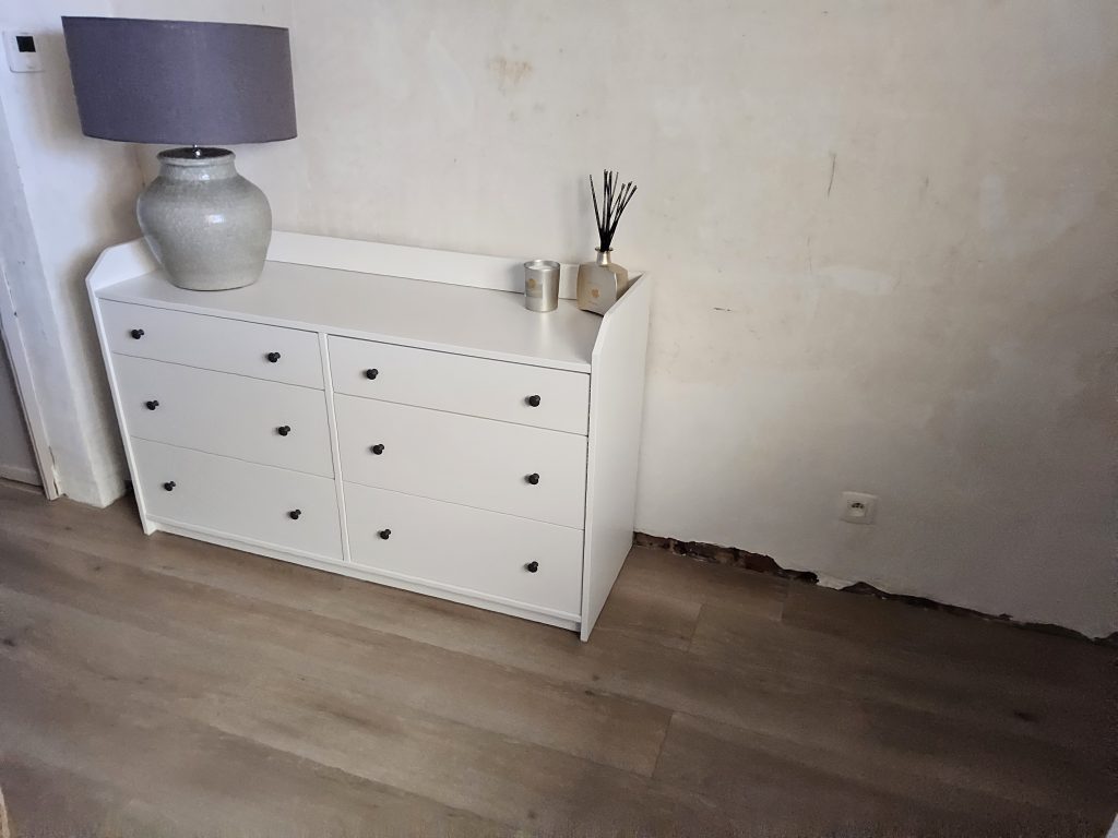 Afbladderende muur onder dressoir, een gevolg schimmel door opstijgend vocht.