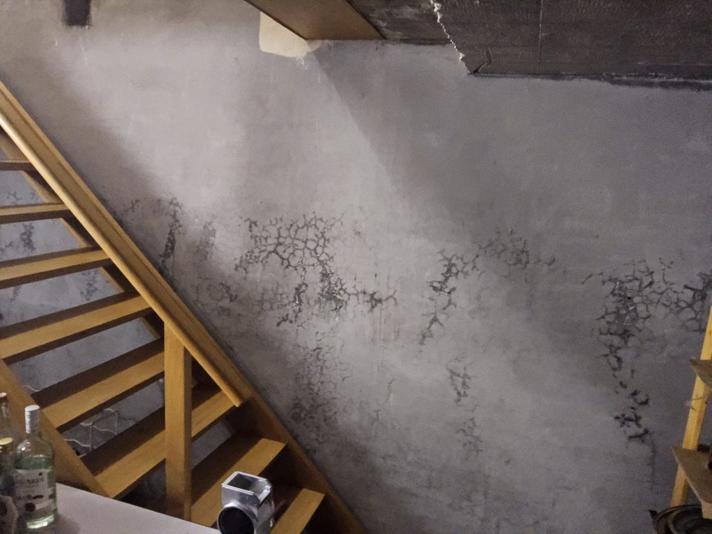 Vochtplekken en scheurtjes op een keldermuur als gevolg van condensatievocht